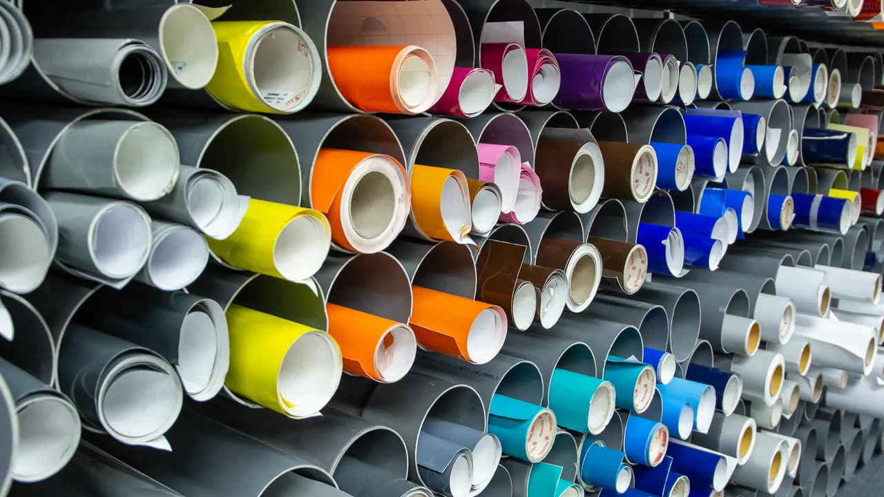 Estantería de bobinas de vinilo de colores para el rotulado de corte en la nave de Dyreco