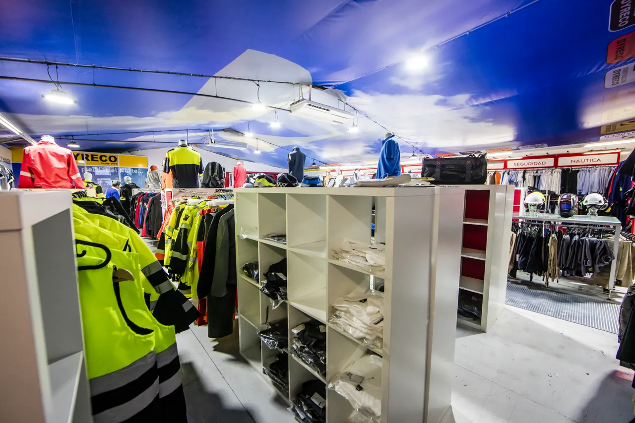 Sala de uniformidad de Dyreco con estanterías de material de seguridad, ropa de alta visibilidad y las zonas rotuladas de seguridad y náutica