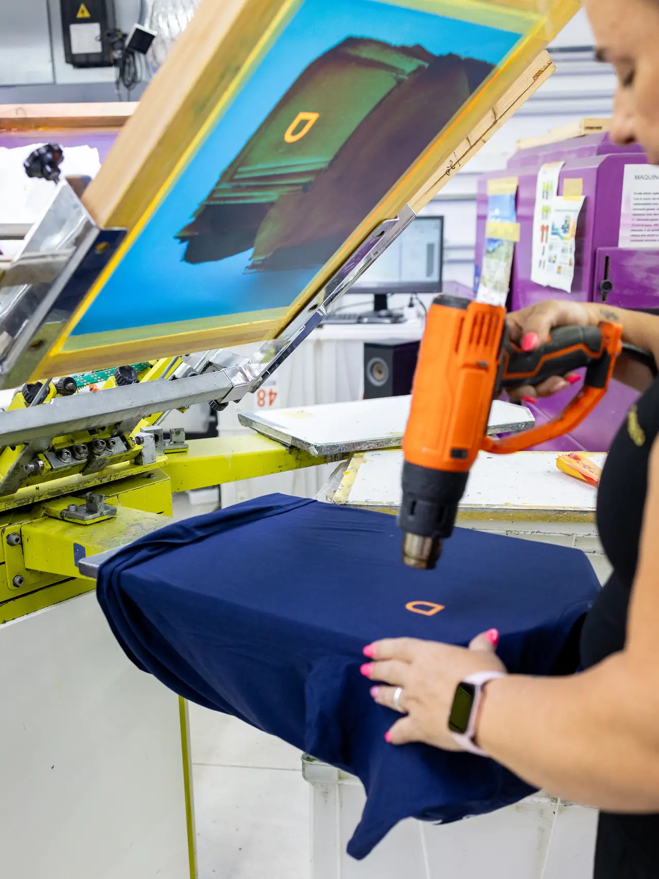 Operaria del taller de Dyreco secando con pistola de calor la tinta de una camiseta serigrafiada