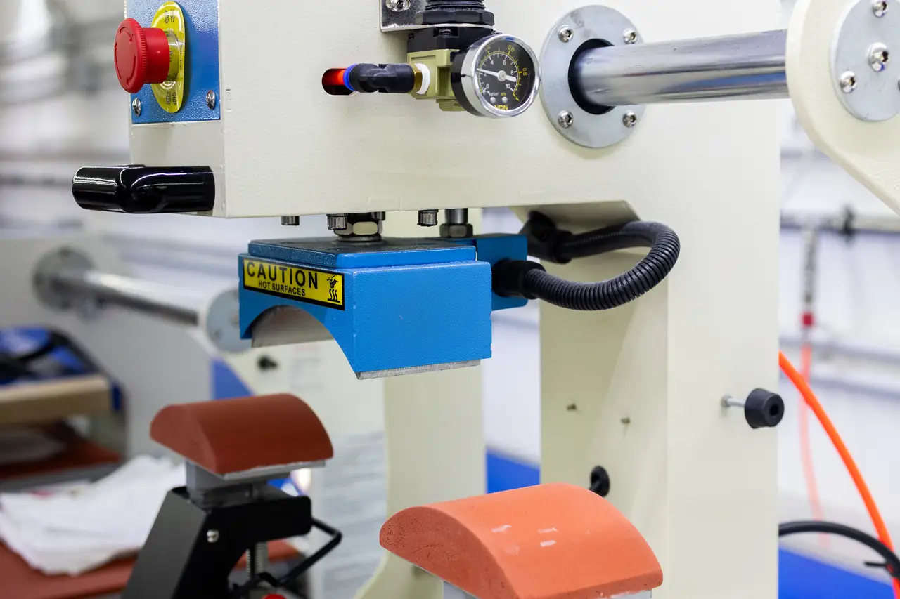 Prensa térmica del taller de Dyreco para aplicar el transfer, con los platos curvos para gorras