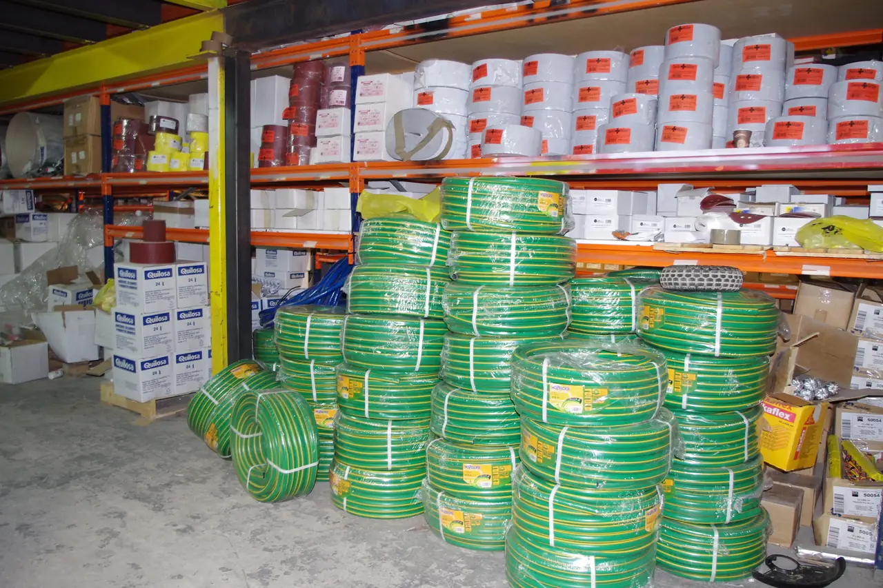 Mangueras de riego apiladas junto a cajas de selladores en el almacén de Dyreco